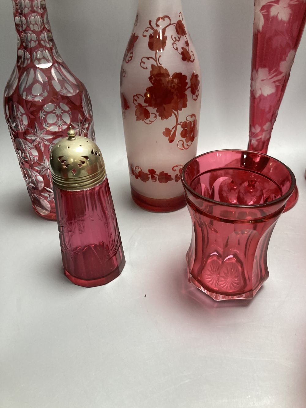A collection of nine pieces of cranberry and ruby coloured glass, including a pair of decanters, two vases and a carafe and tumbler